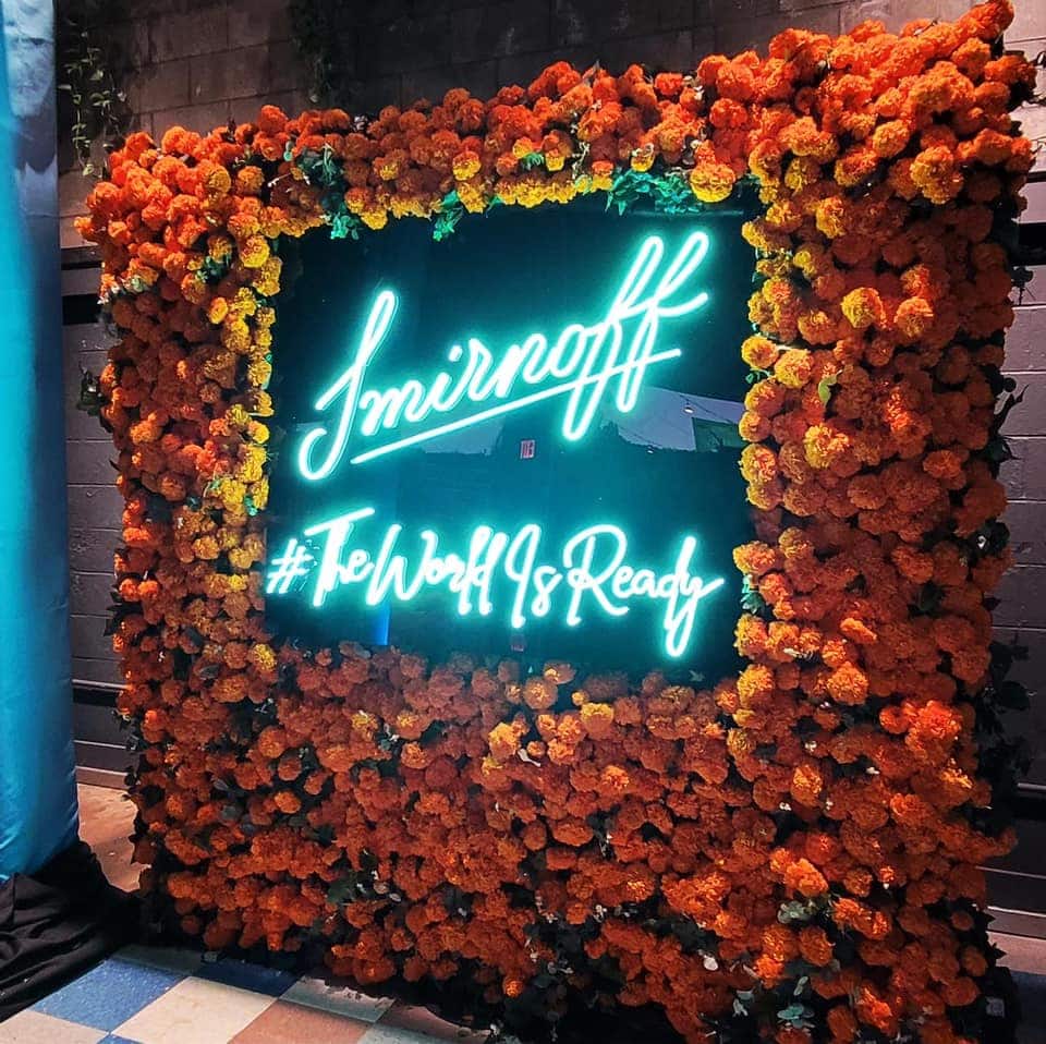 Smirnoff neon sign surrounded by orange flowers.