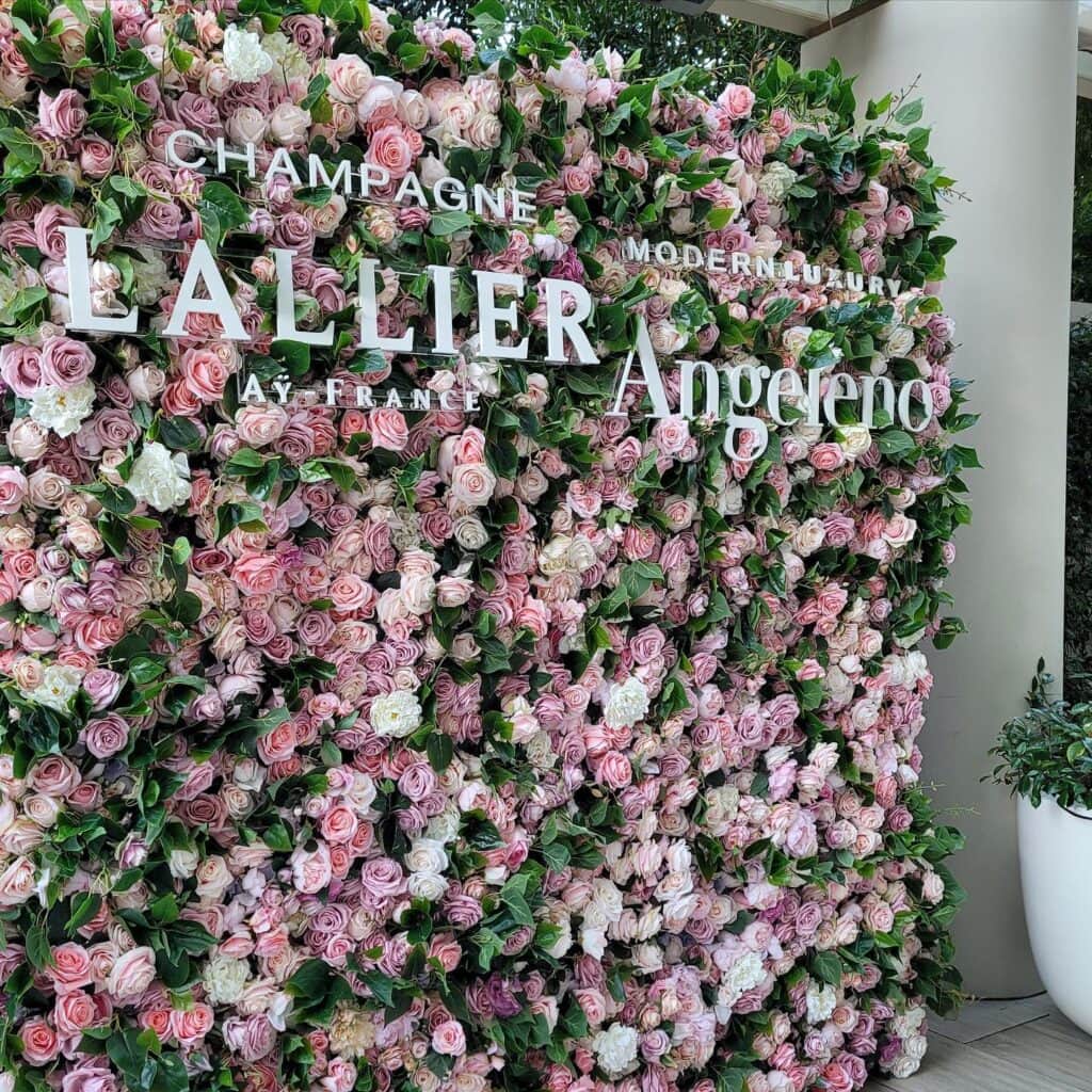 Floral wall with Lallier Champagne and Angeleno logos.