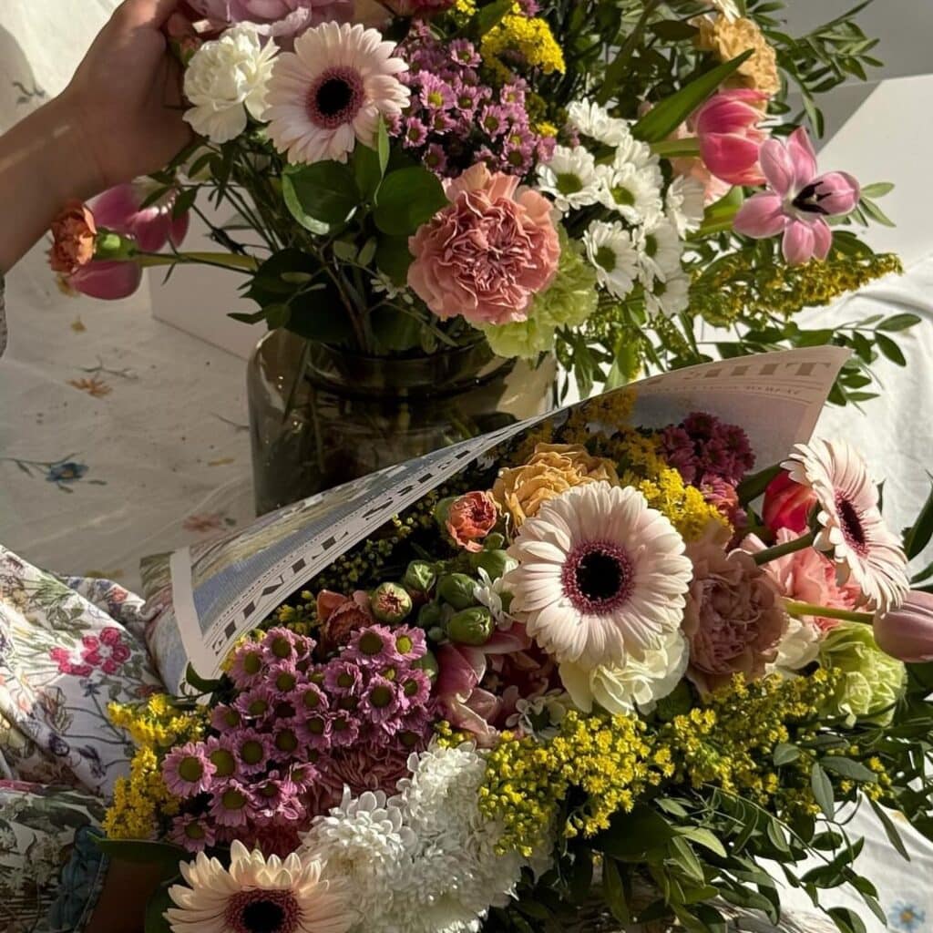 Person arranging colorful bouquet of flowers