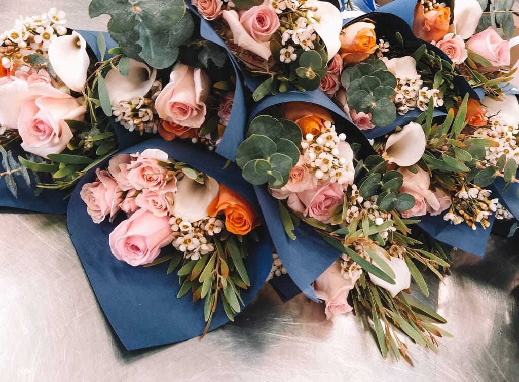 Beautiful bouquets of roses and greenery wrapped in blue paper.