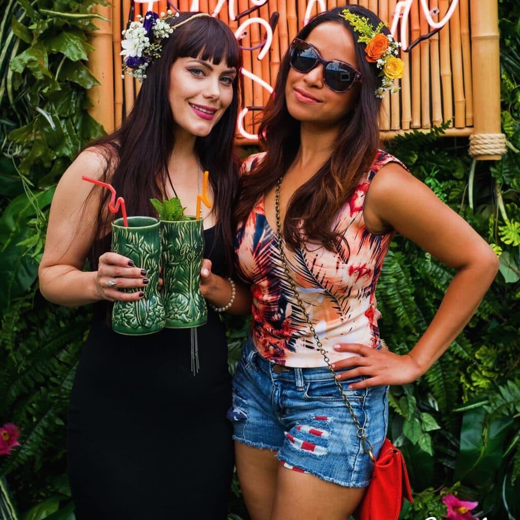 Two women holding drinks at a garden party.
