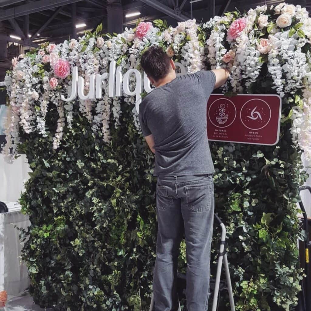 Person decorating floral display with sign
