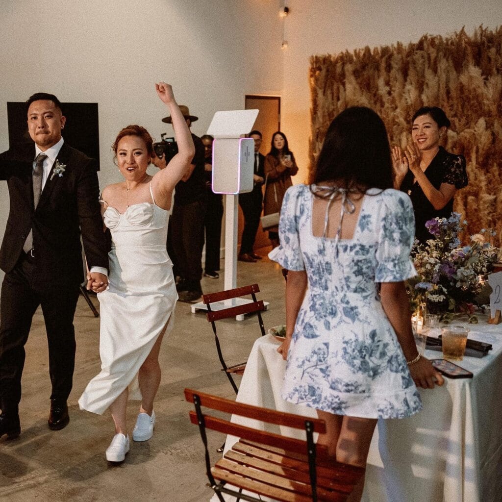 Happy couple entering wedding reception, guests clapping.